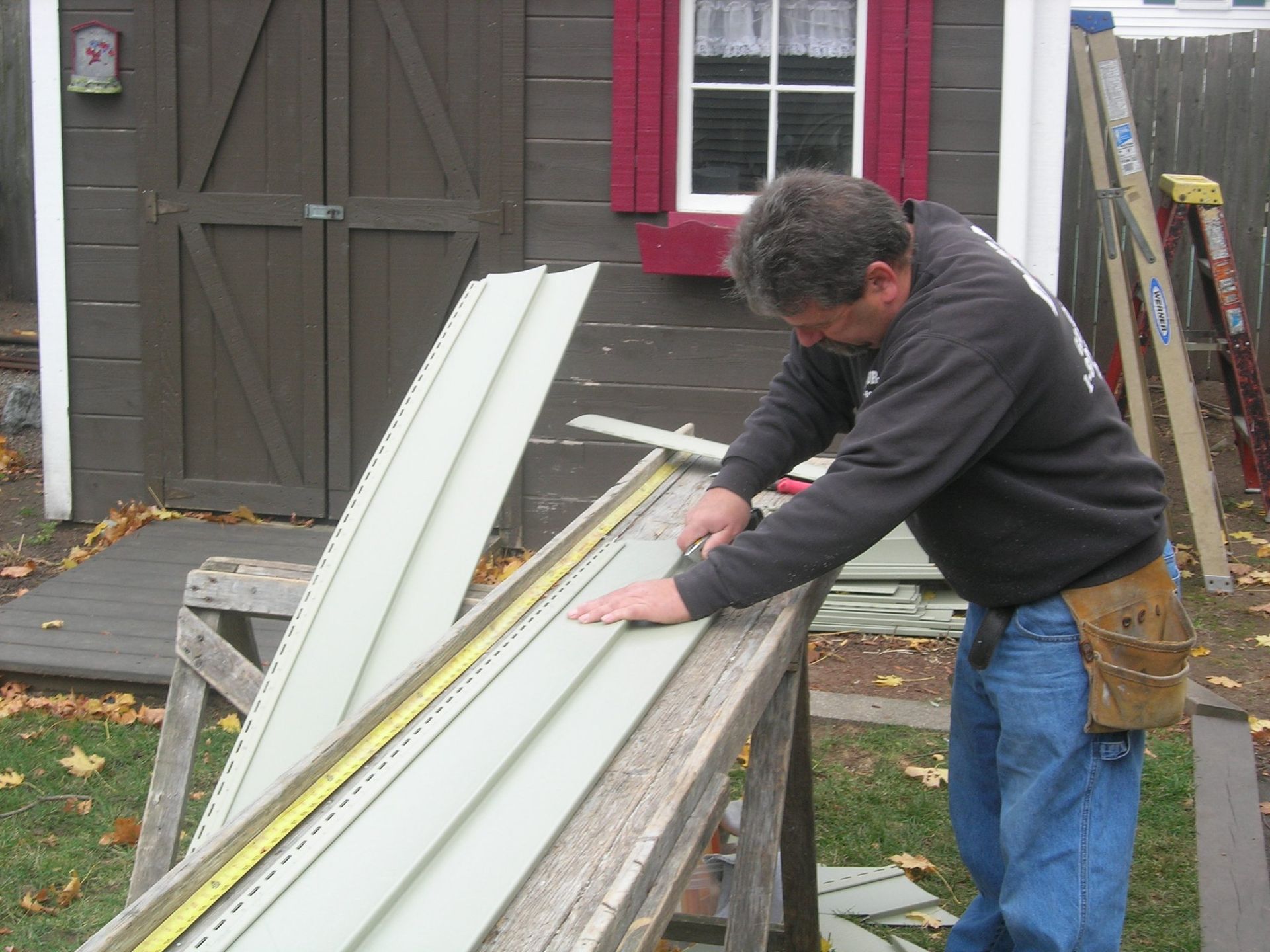 A man measuring a piece of siding with a tape measure