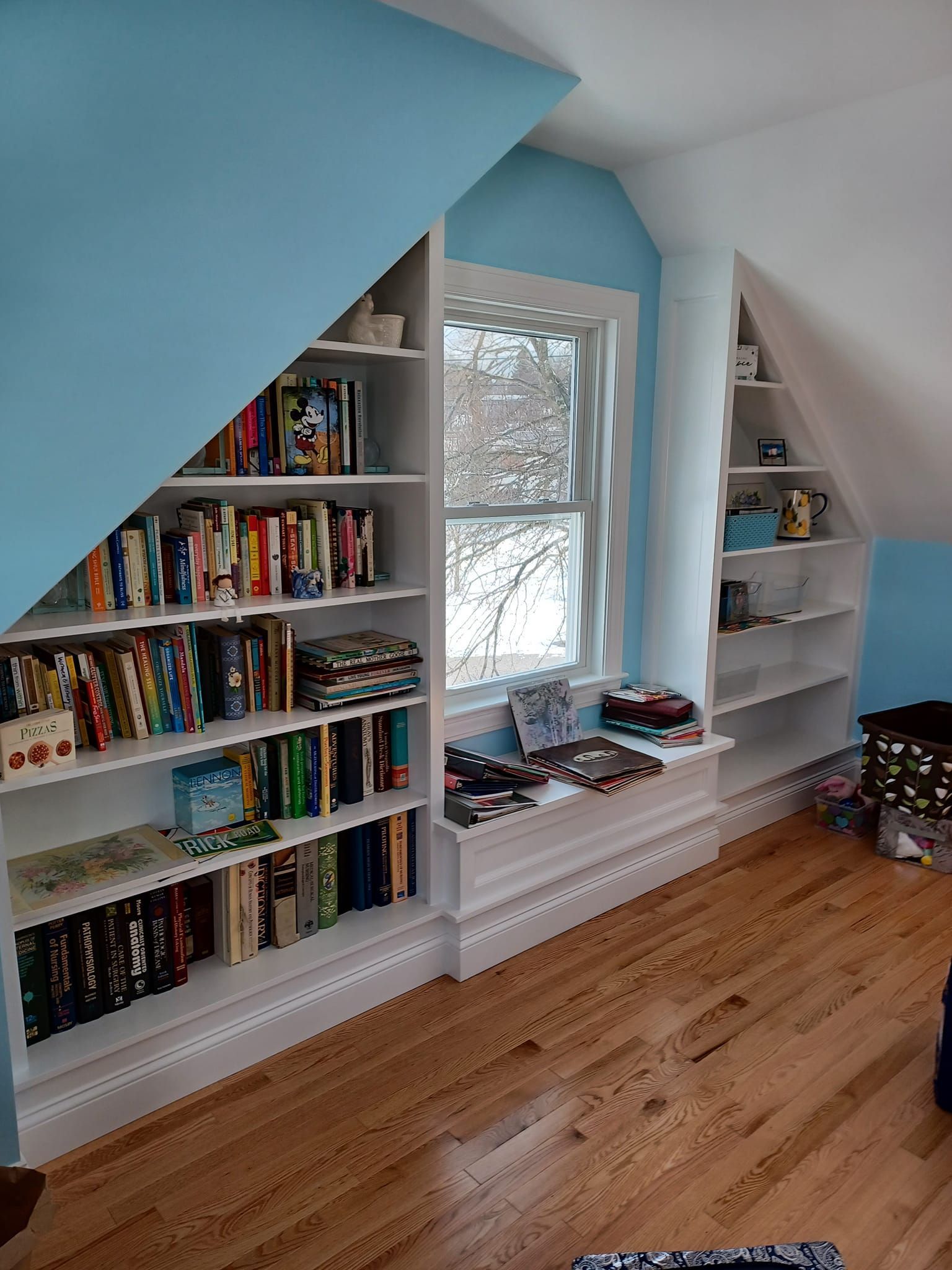 A room with a lot of books on the shelves and a window.