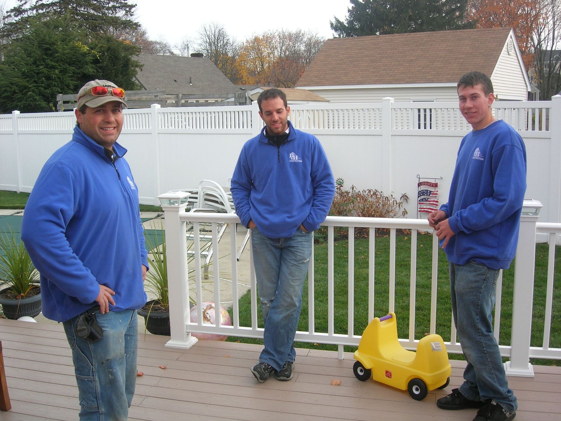 Three men standing on a deck with a yellow toy car