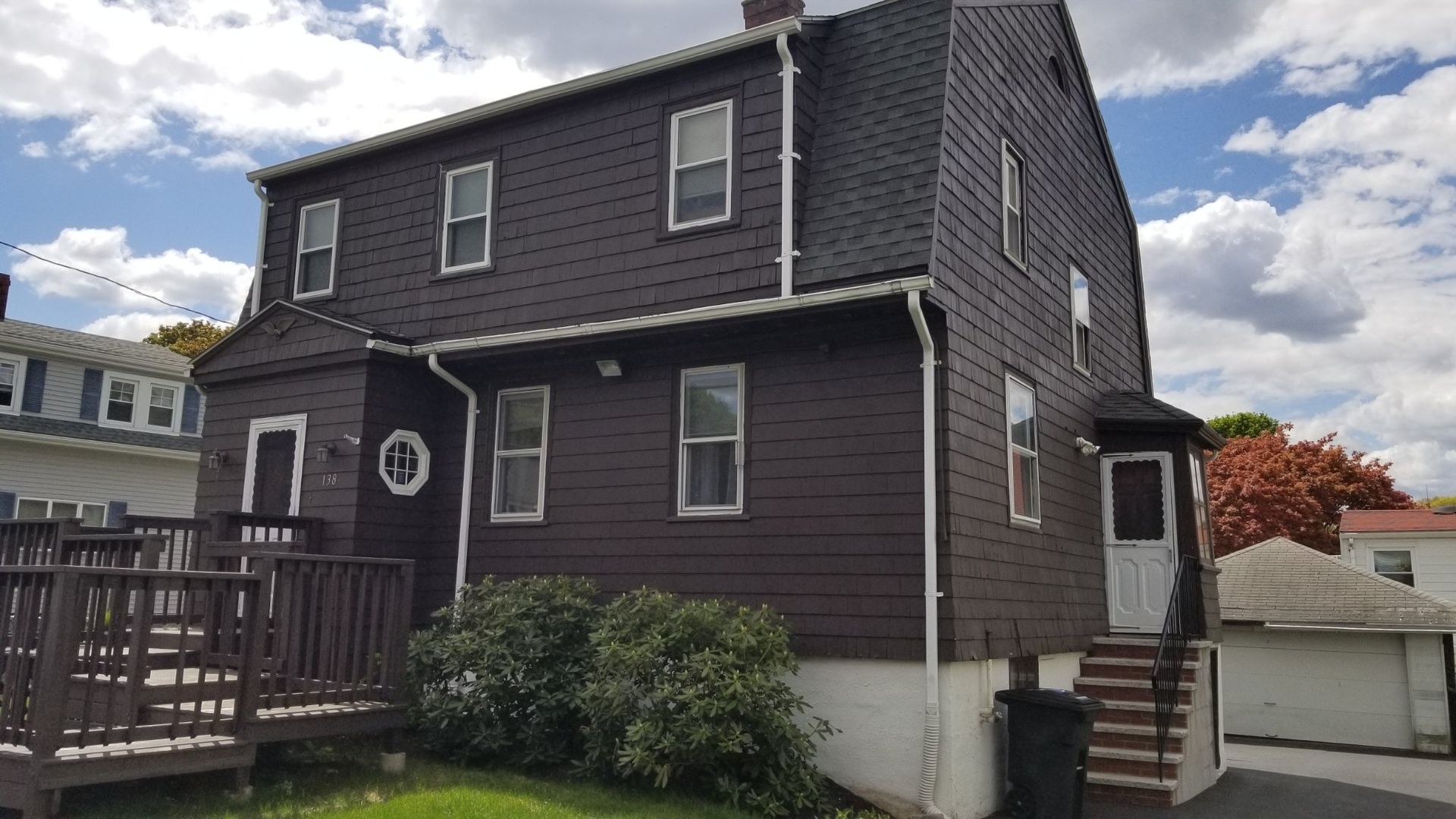 A large brown house with a deck and stairs