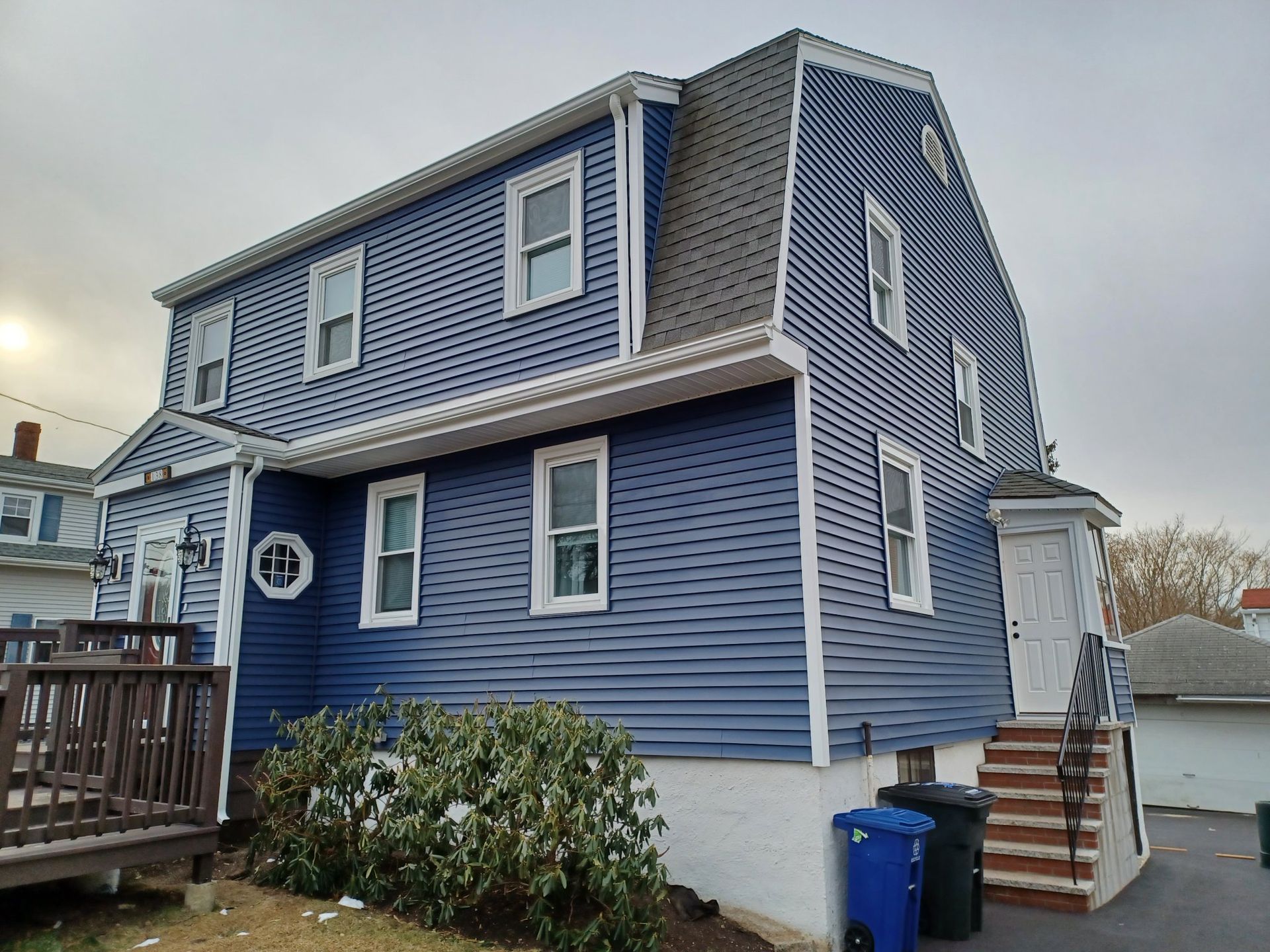 A blue house with white trim and a gray roof