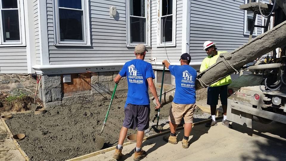 Two men in blue shirts are standing in front of a concrete truck.