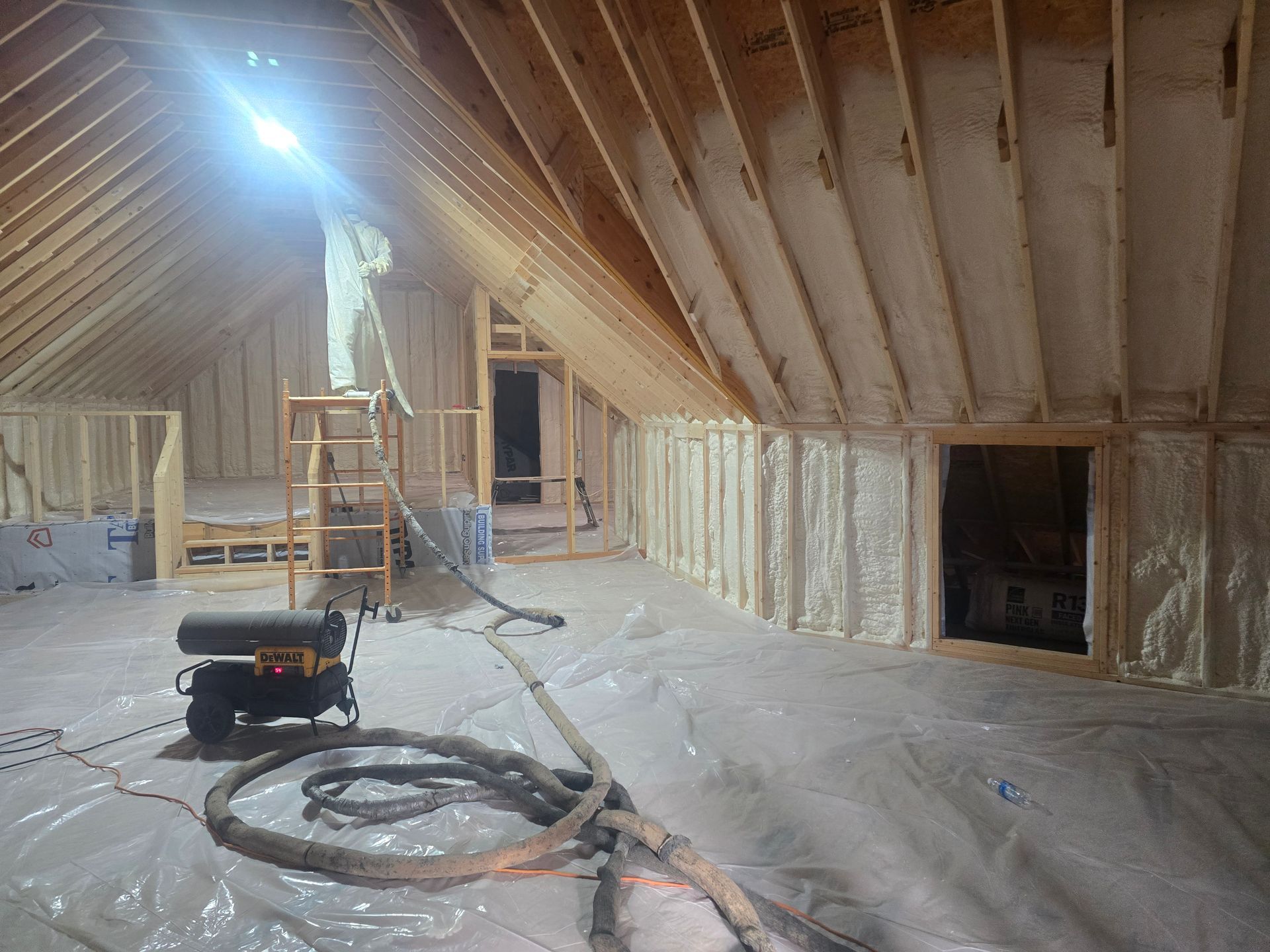 Man spraying insulation in a wooden attic.