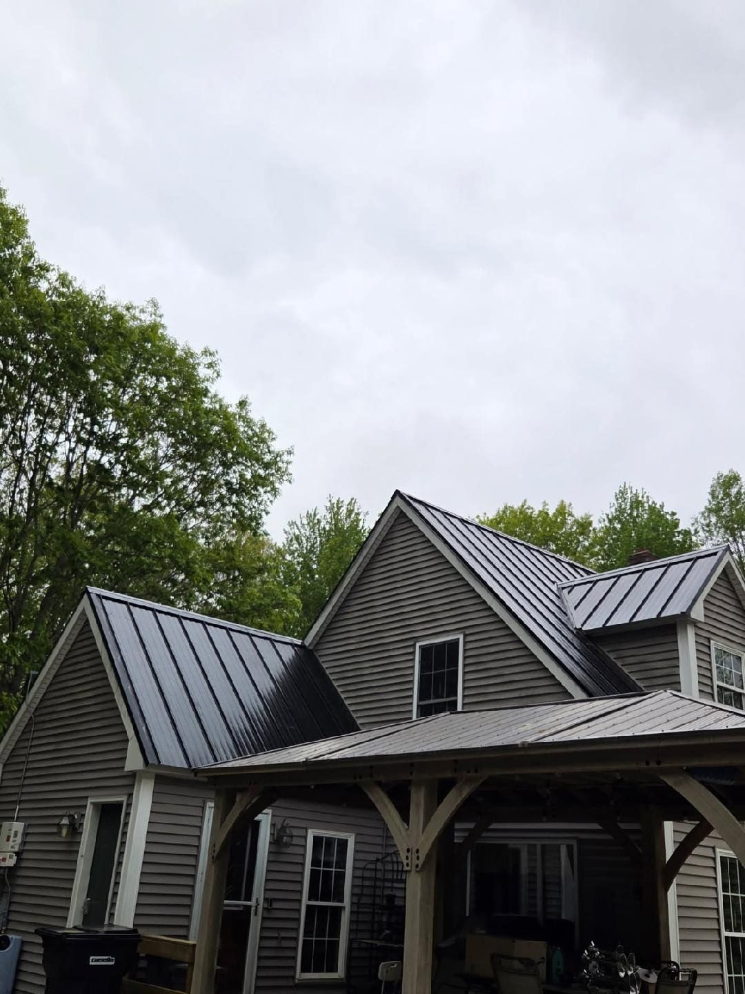 A house with a metal roof and a porch on a cloudy day.