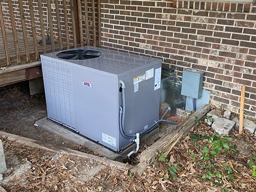 An air conditioner is sitting on the side of a brick building.