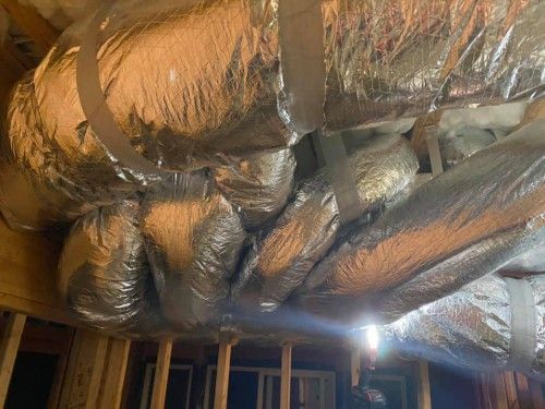 A bunch of ducts are hanging from the ceiling of a building.