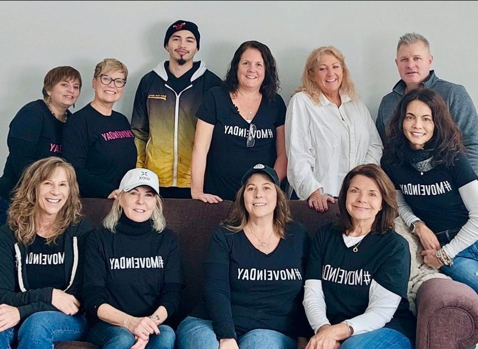 Group of people in black shirts, posing together indoors.