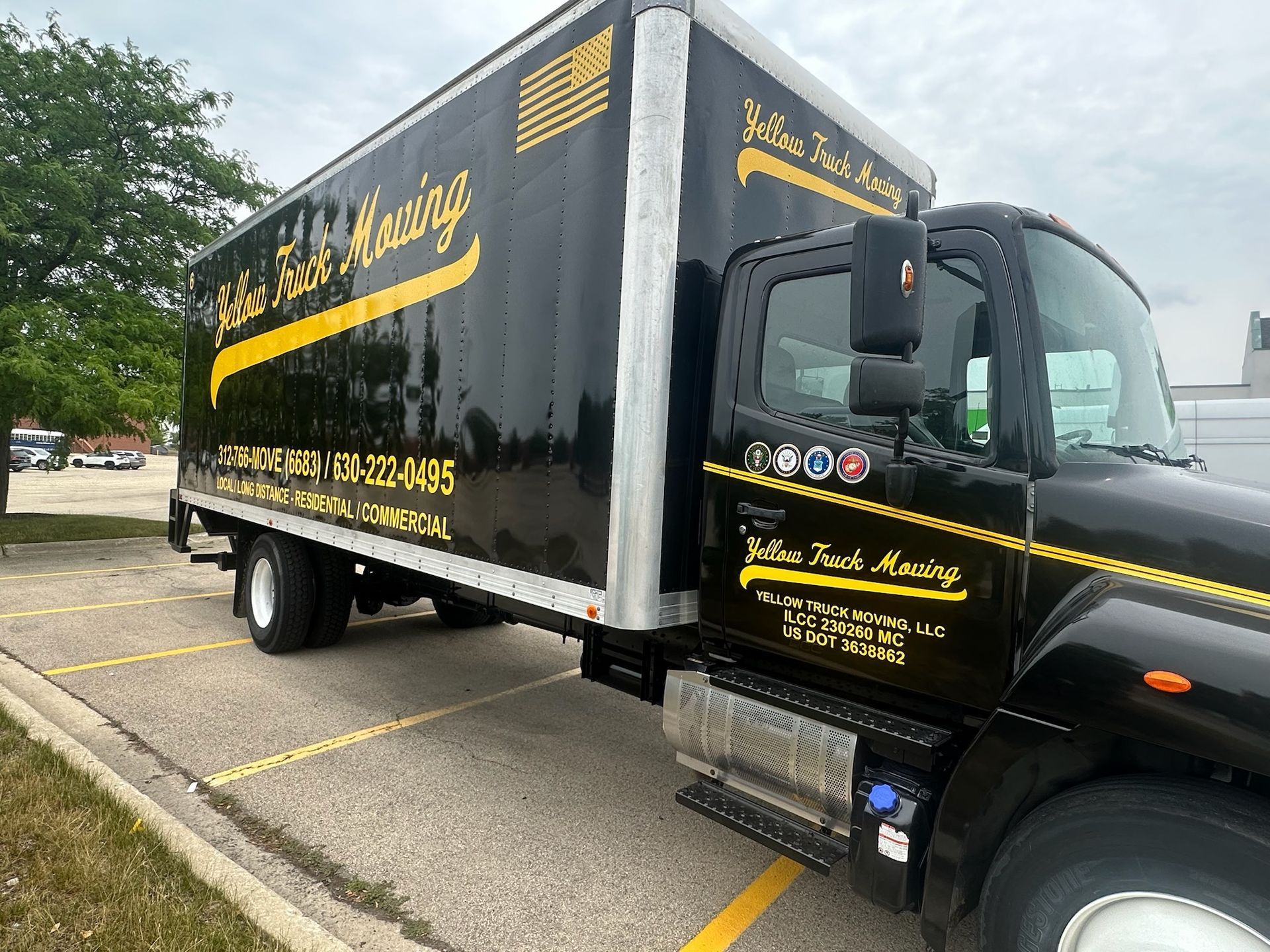 Black moving truck parked on asphalt; yellow lettering: 