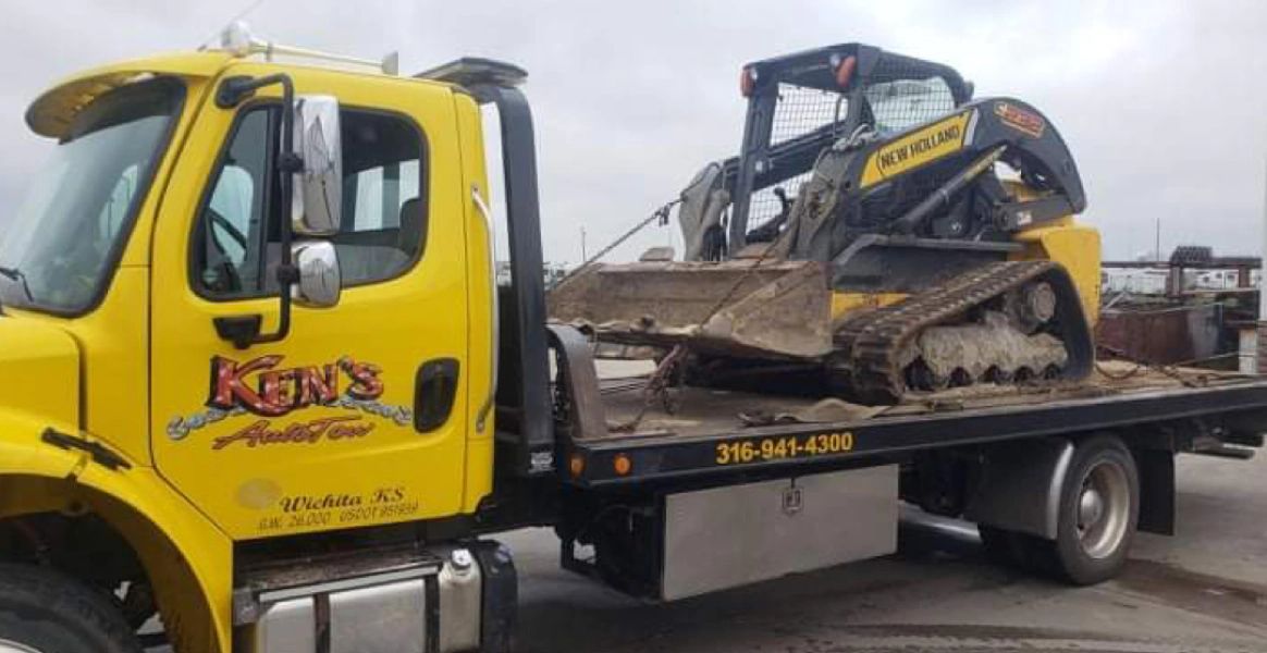 A yellow tow truck is carrying a bulldozer on the back of it.
