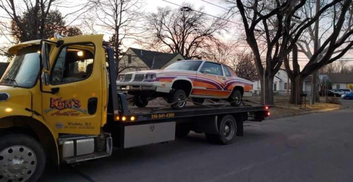 A tow truck is carrying a car on the back of it.
