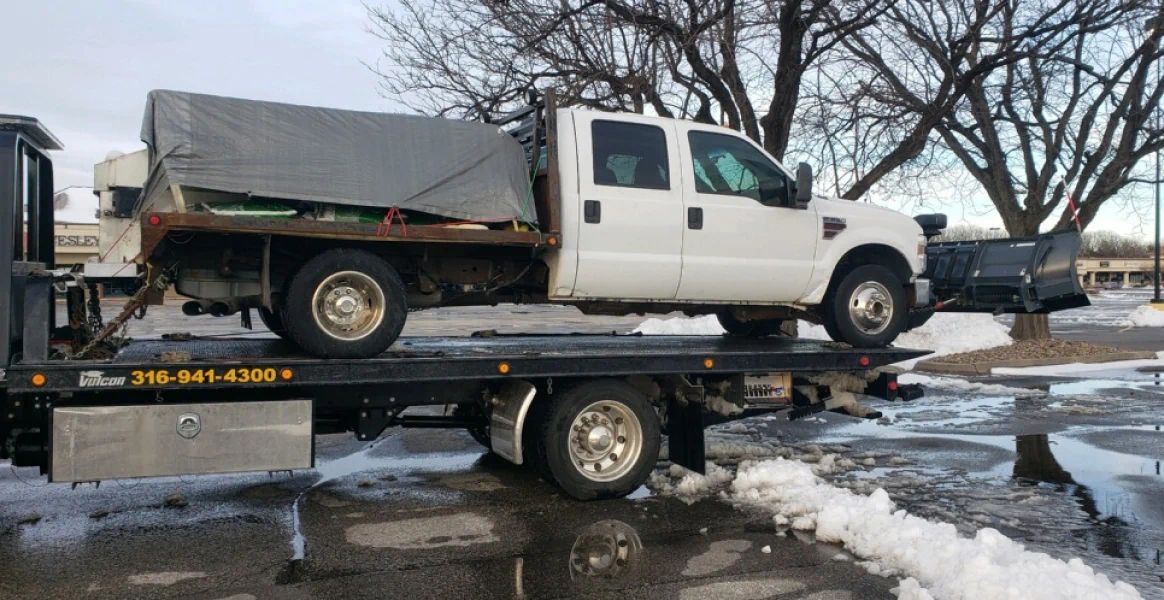 A white truck is sitting on top of a flatbed tow truck.