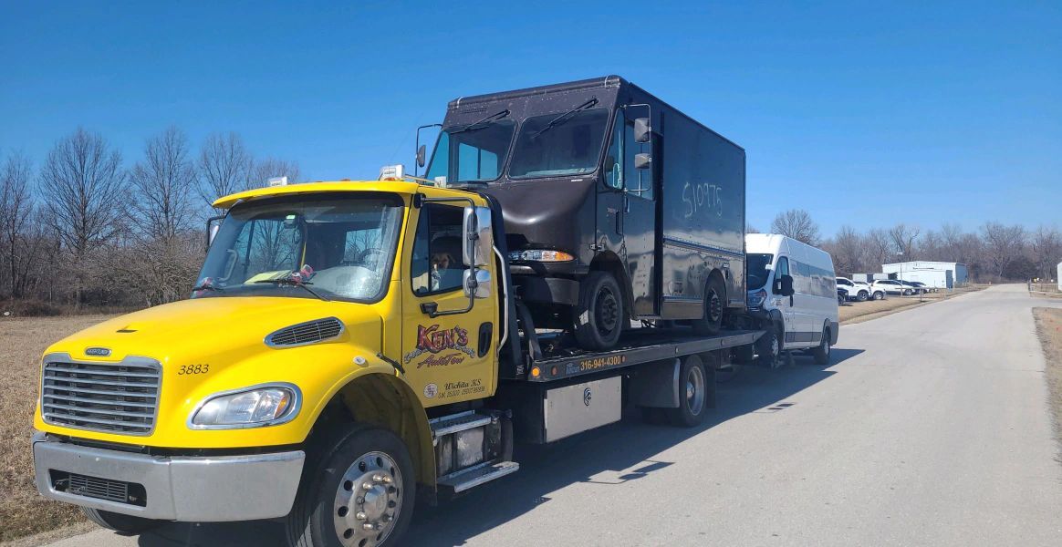 A yellow tow truck is carrying a truck on the back of it.