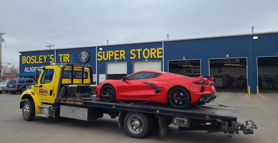 A red sports car is being towed by a tow truck.