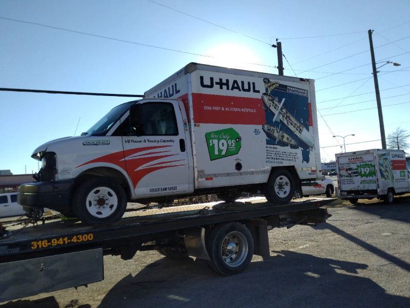 A u-haul truck is sitting on top of a tow truck