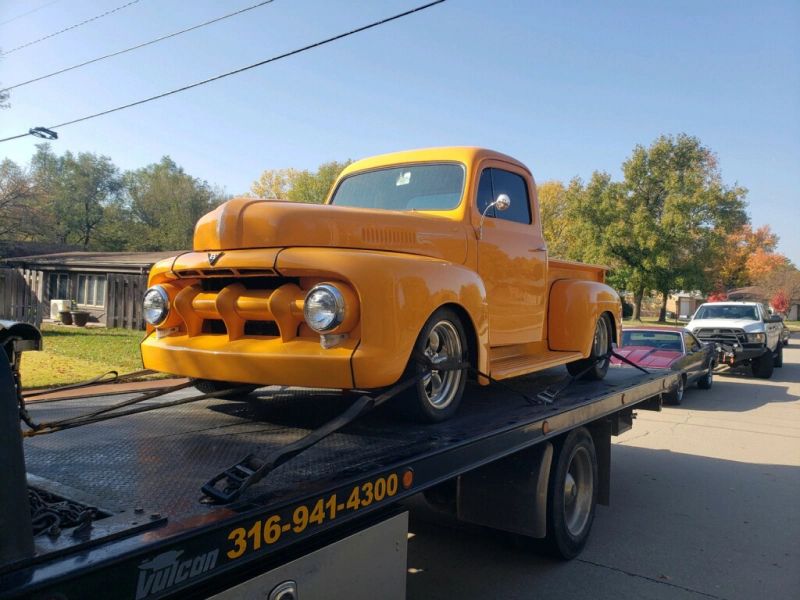 A yellow truck is sitting on top of a tow truck.