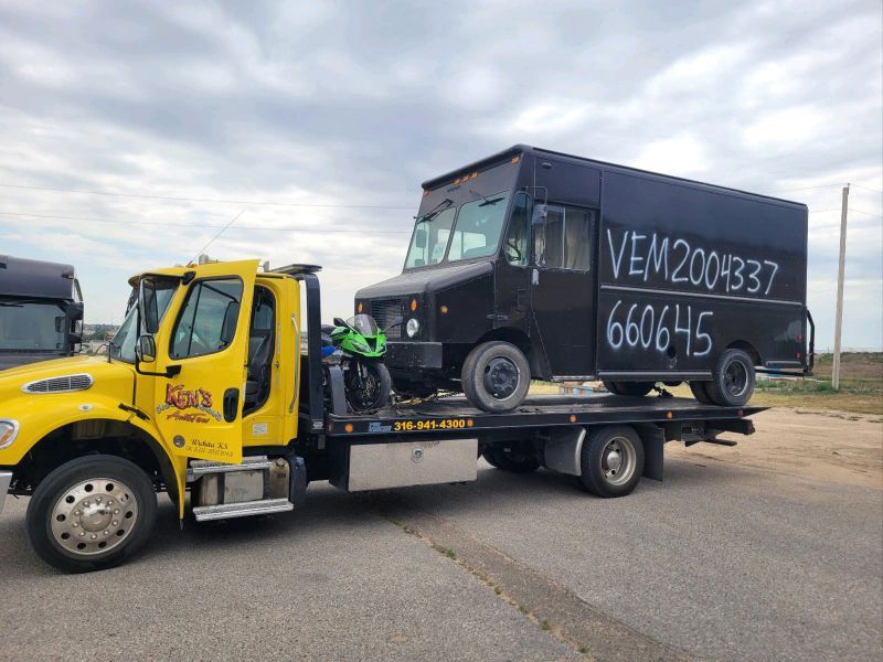 A yellow tow truck is towing a black van.