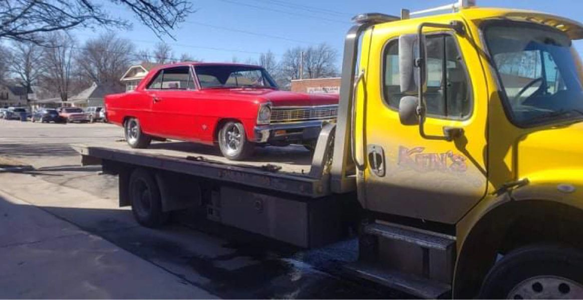 A yellow tow truck is towing a red car.