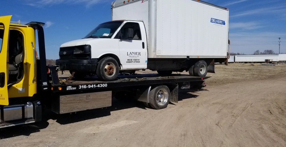 A white van is sitting on top of a yellow tow truck.