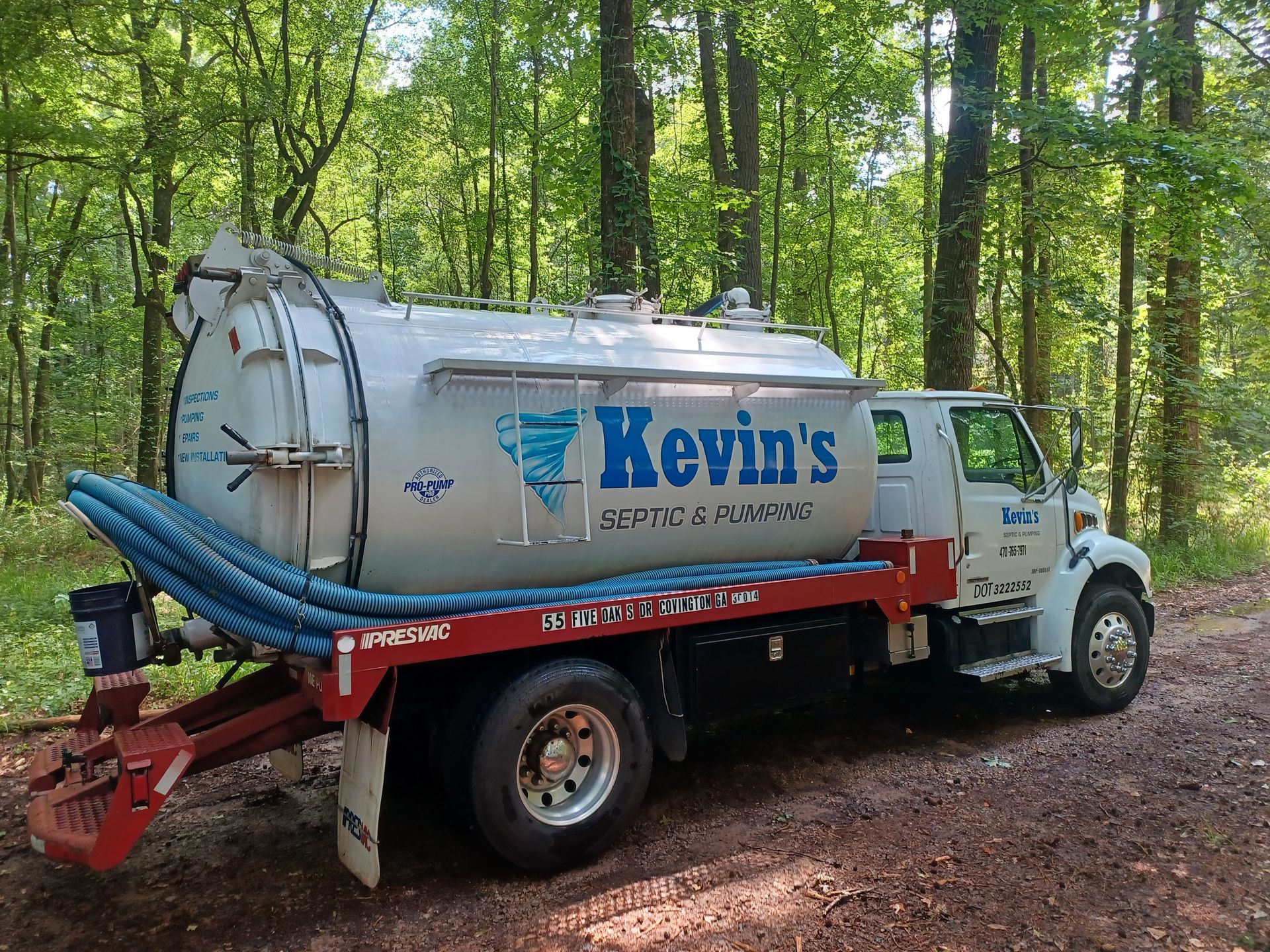 A septic pumping truck, Kevin's Septic & Pumping, parked on a dirt road in a wooded area.