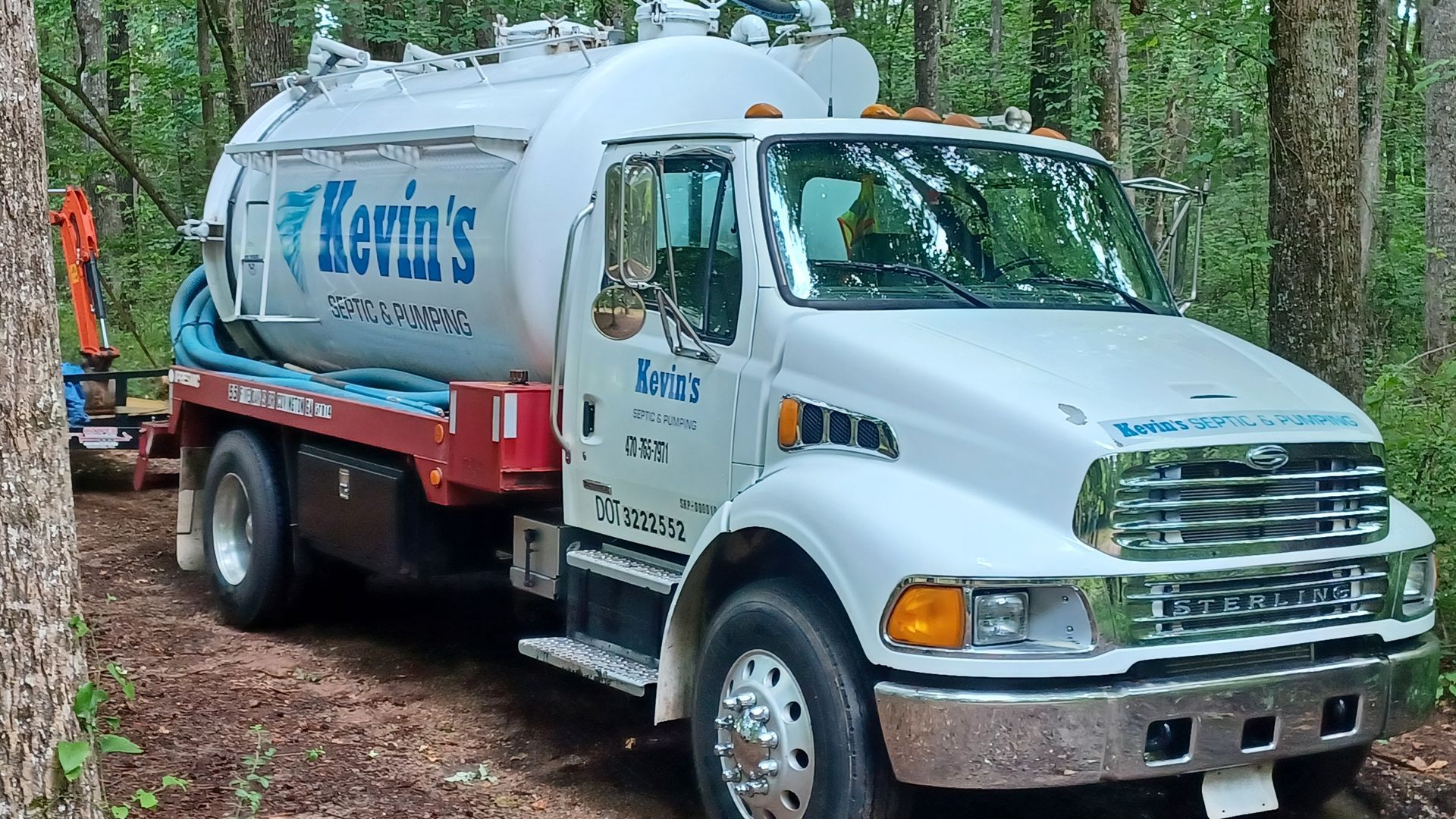 White septic tank truck labeled Kevin's Septic parked on a dirt road in a wooded area.