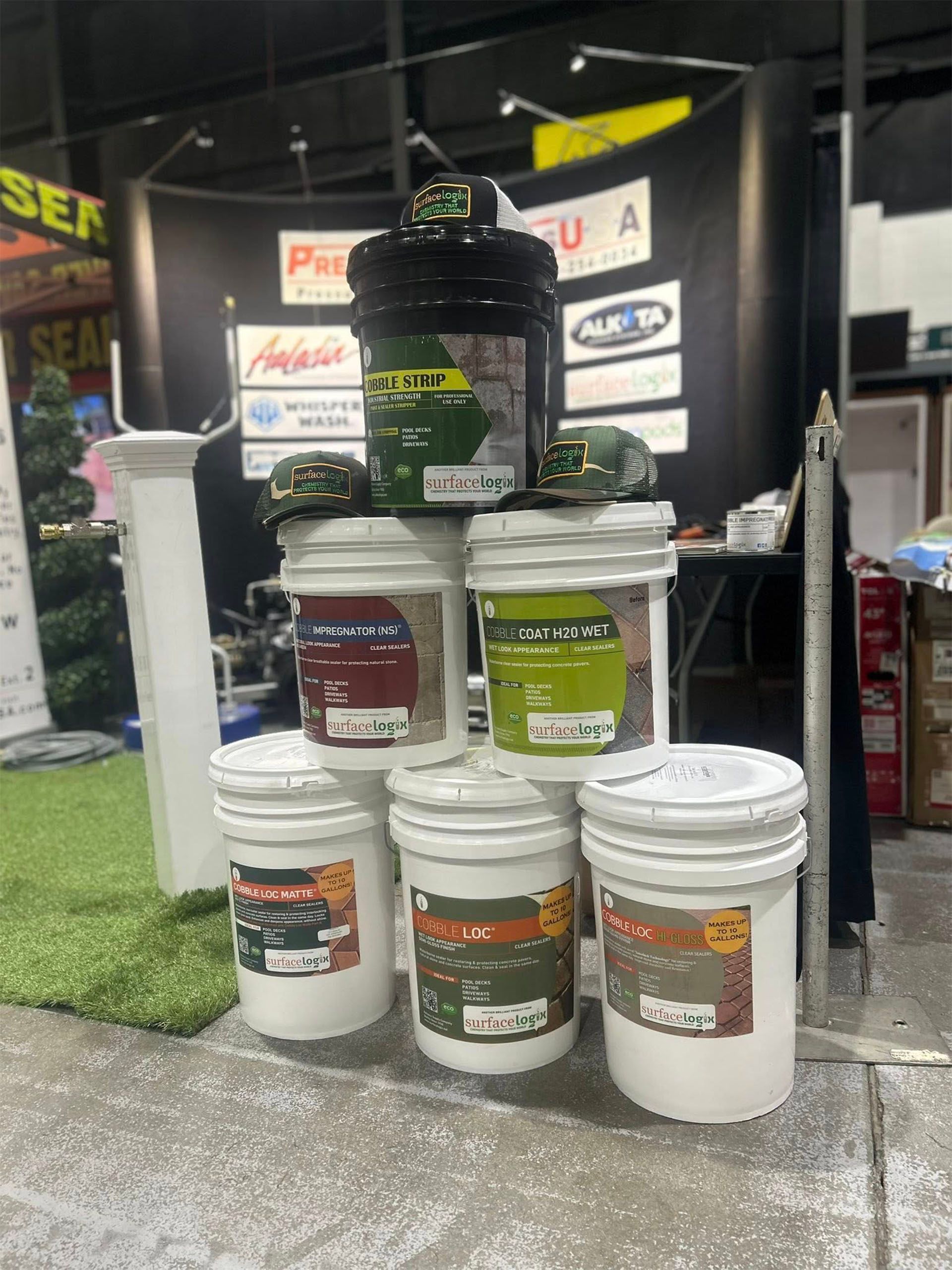 Buckets of paint and coatings displayed on a trade show booth table.