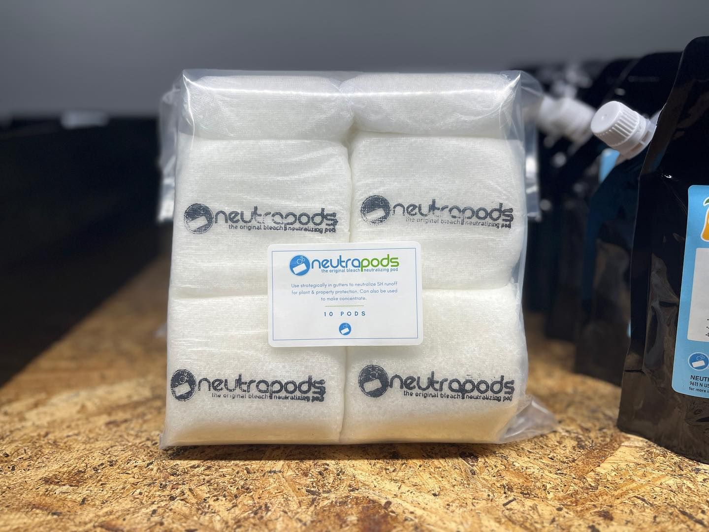 Stack of white packaged goods with Neutropods labels on a countertop, beside a blue bottle.
