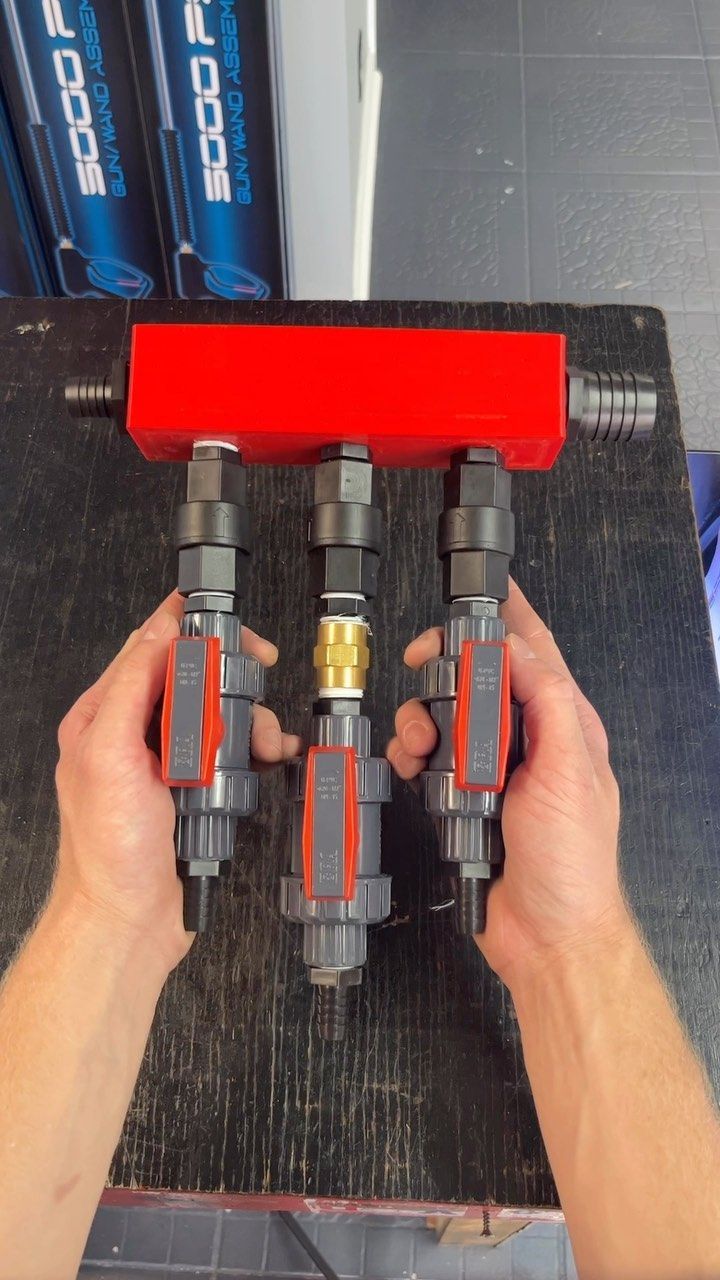 Hands holding a black device with a bright red top and three gray-and-red cylindrical components.
