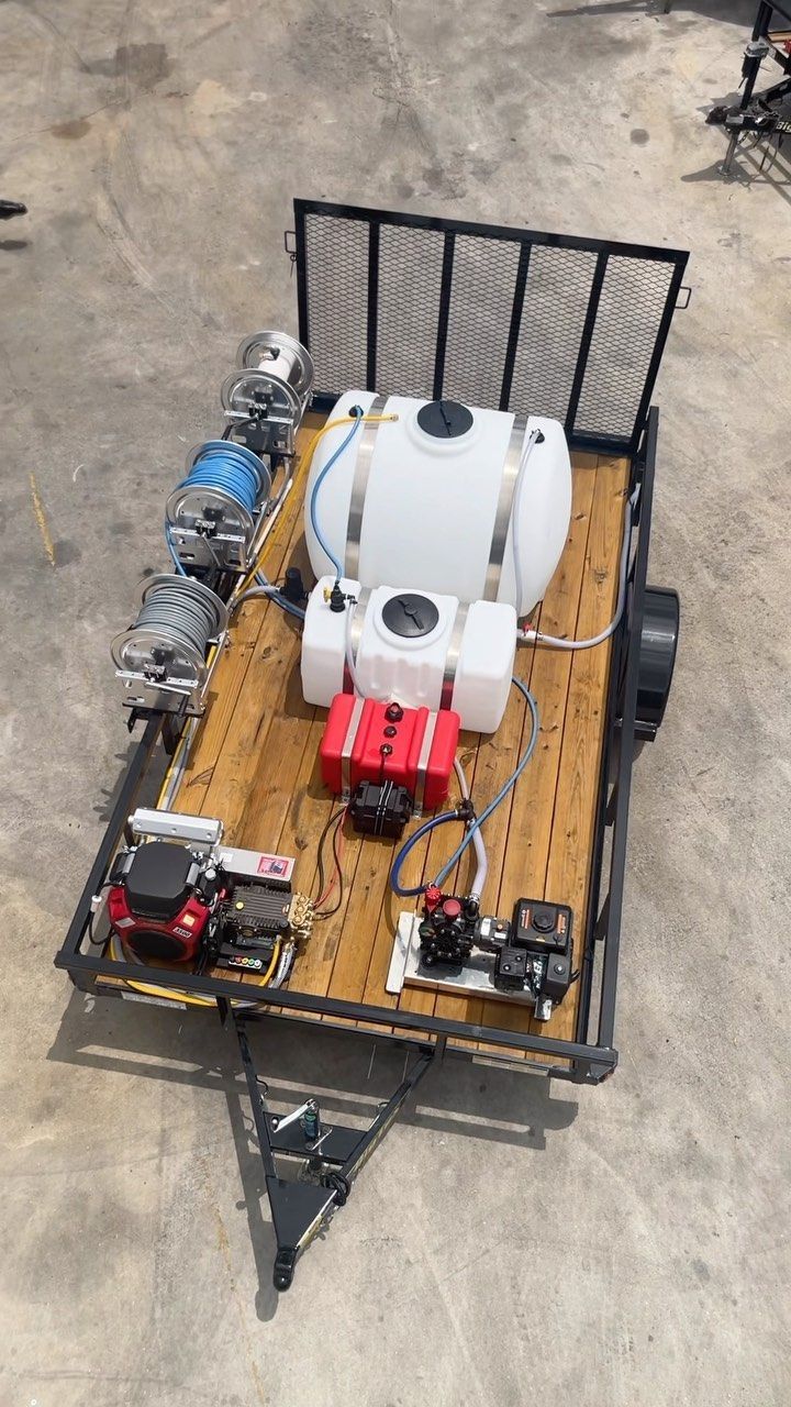 Small wheeled cart with tanks, engine parts, and a metal frame on a concrete surface.