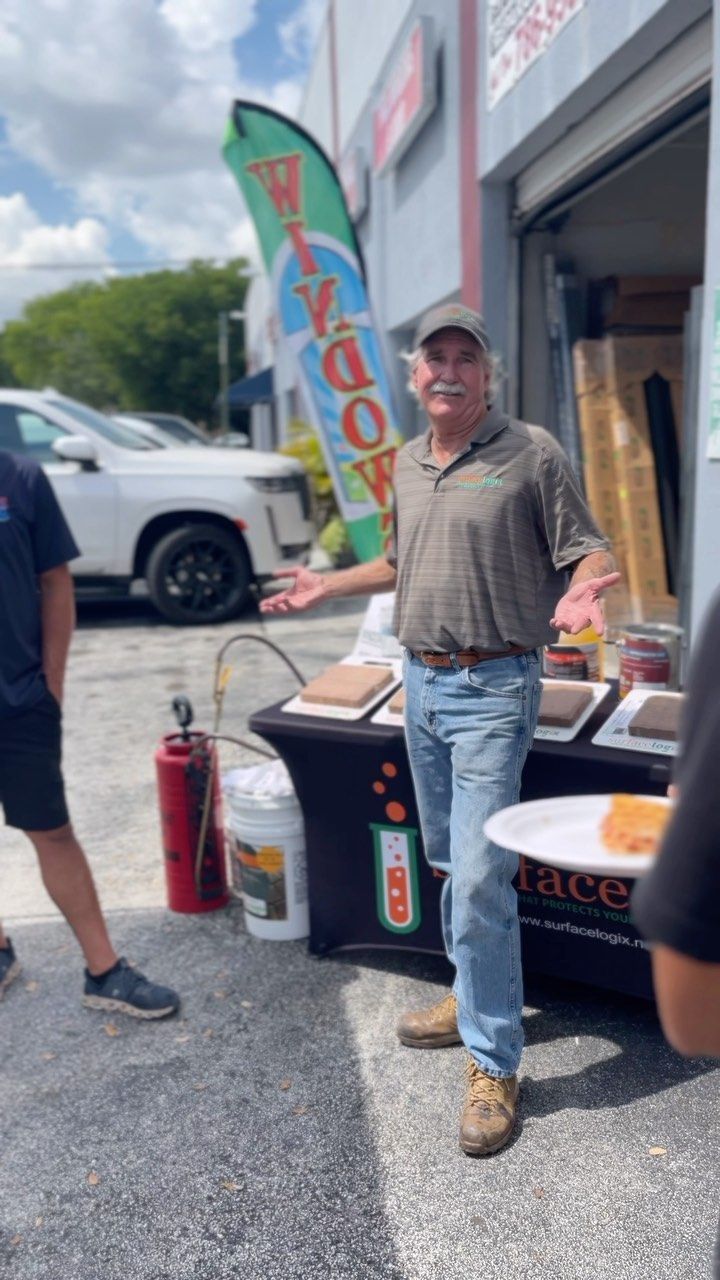 Man standing beside a food stall with coolers, a red fire extinguisher, and a vertical flag on a roadside.