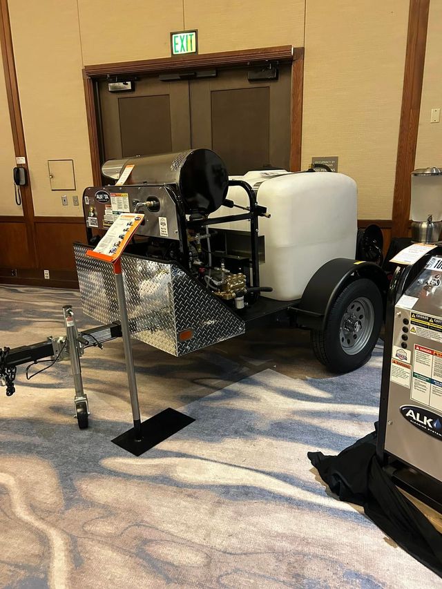 Motorized wheelchair with front basket and white tank, displayed at an indoor conference hall