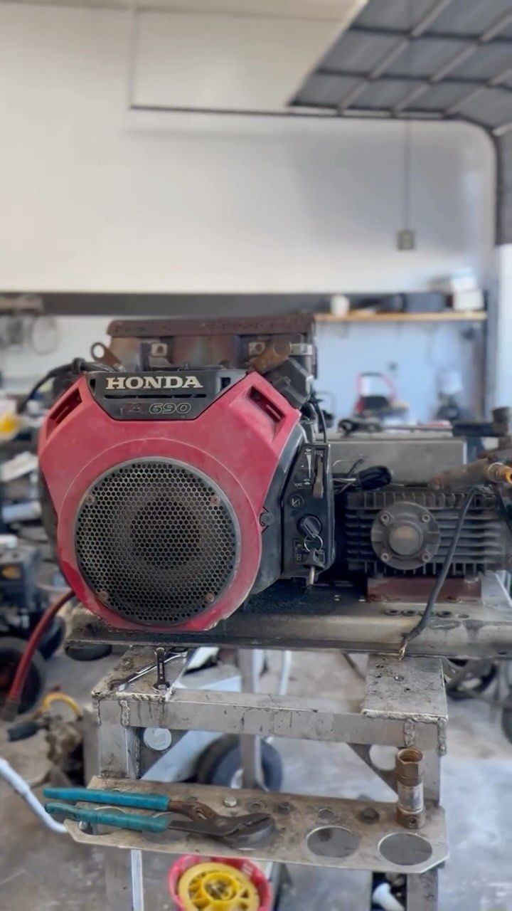 Red Honda engine on a metal frame in a workshop garage.