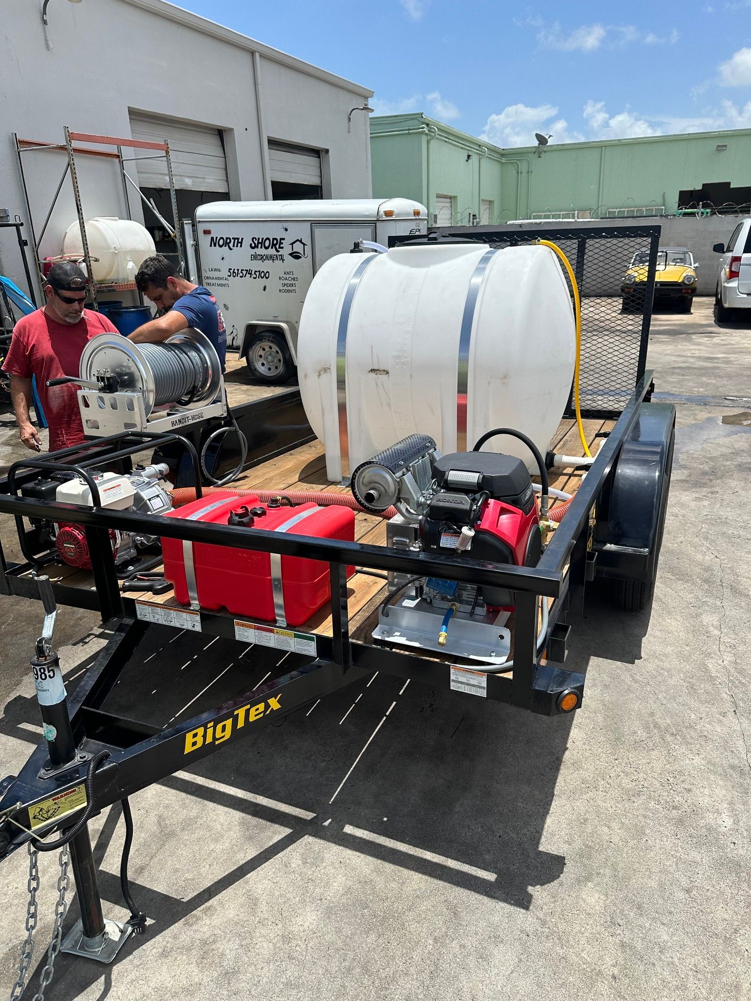 White water tank on a trailer with pumps, parked outdoors near workers and vehicles