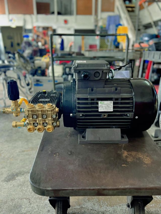 Black electric motor with brass pump assembly on a workbench in a factory workshop