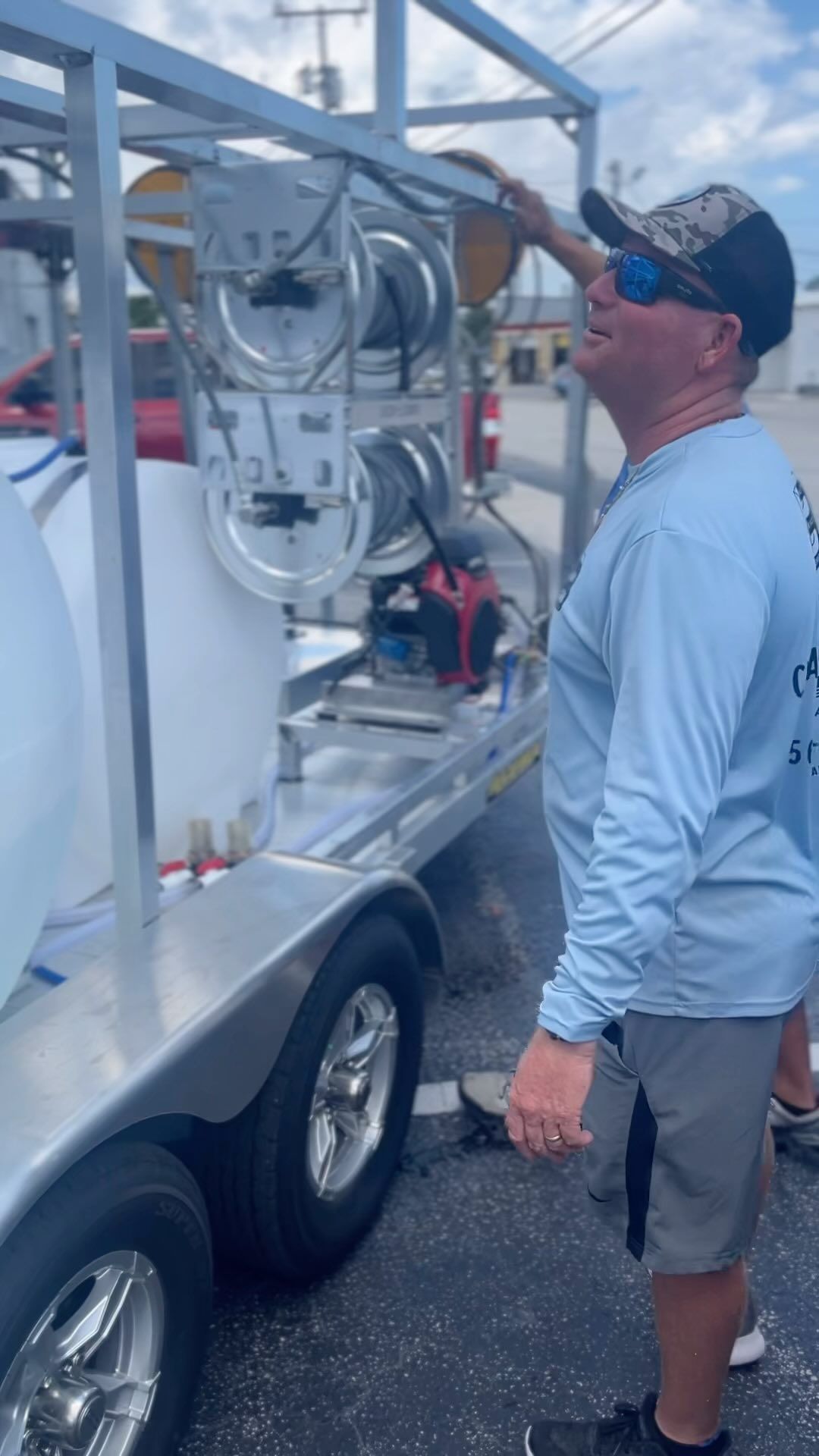 Man adjusting tubing on stainless steel equipment mounted on a trailer outdoors