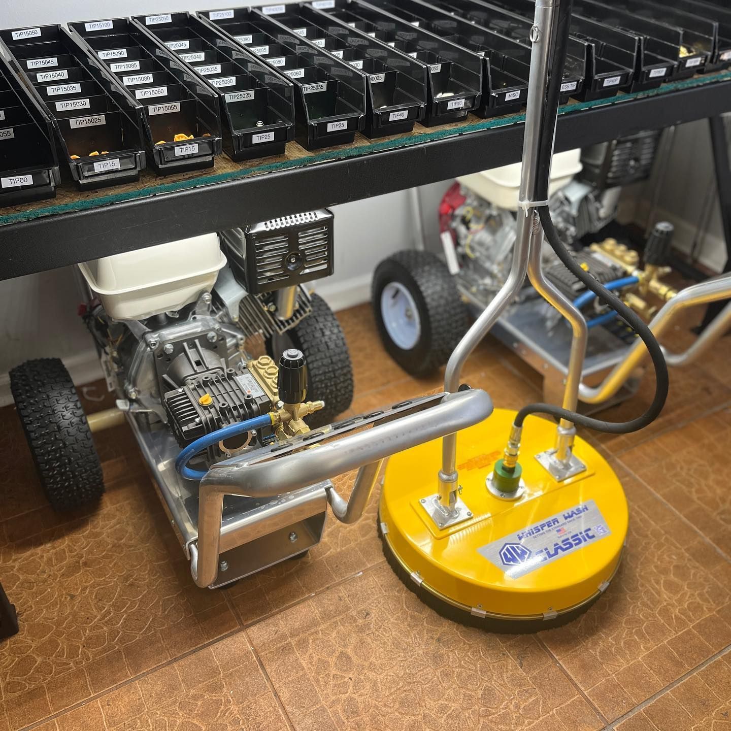Small wheeled robot and yellow round robot chassis under a workbench in a workshop