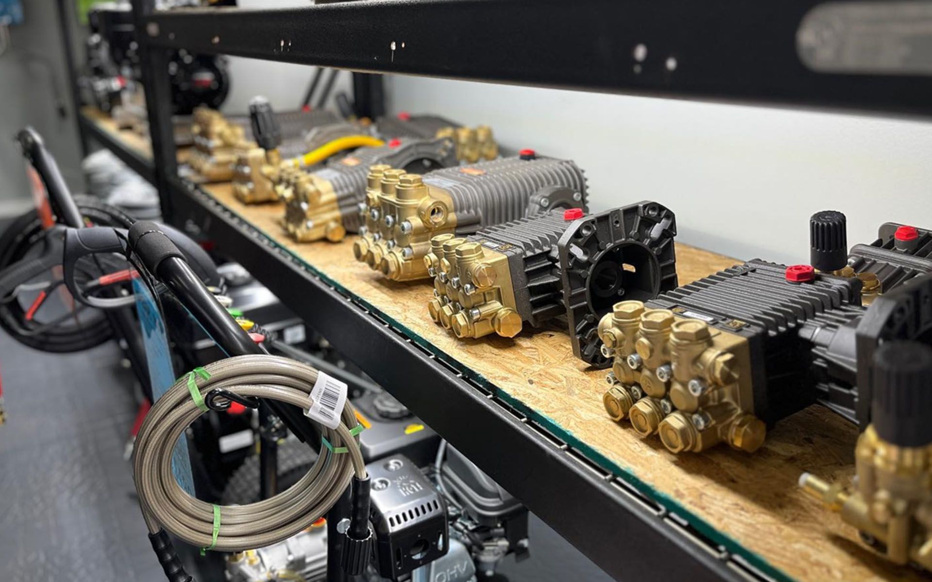 Row of brass industrial pump or compressor units mounted on a black shelf in a workshop.