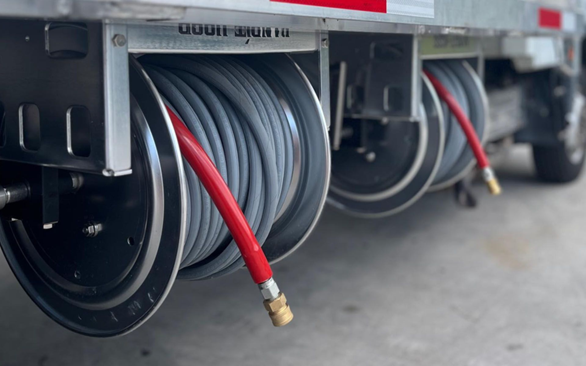 Coiled red and gray hoses on a truck-mounted hose reel at a utility or service vehicle.