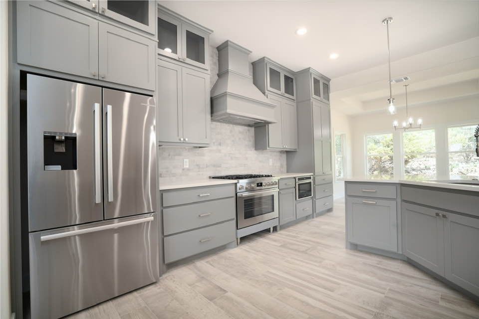A kitchen with stainless steel appliances and gray cabinets.