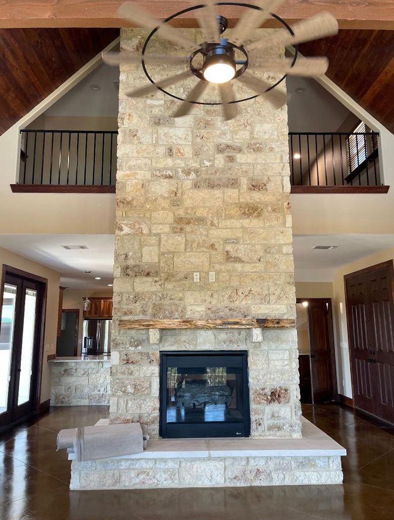 A living room with a fireplace and a ceiling fan