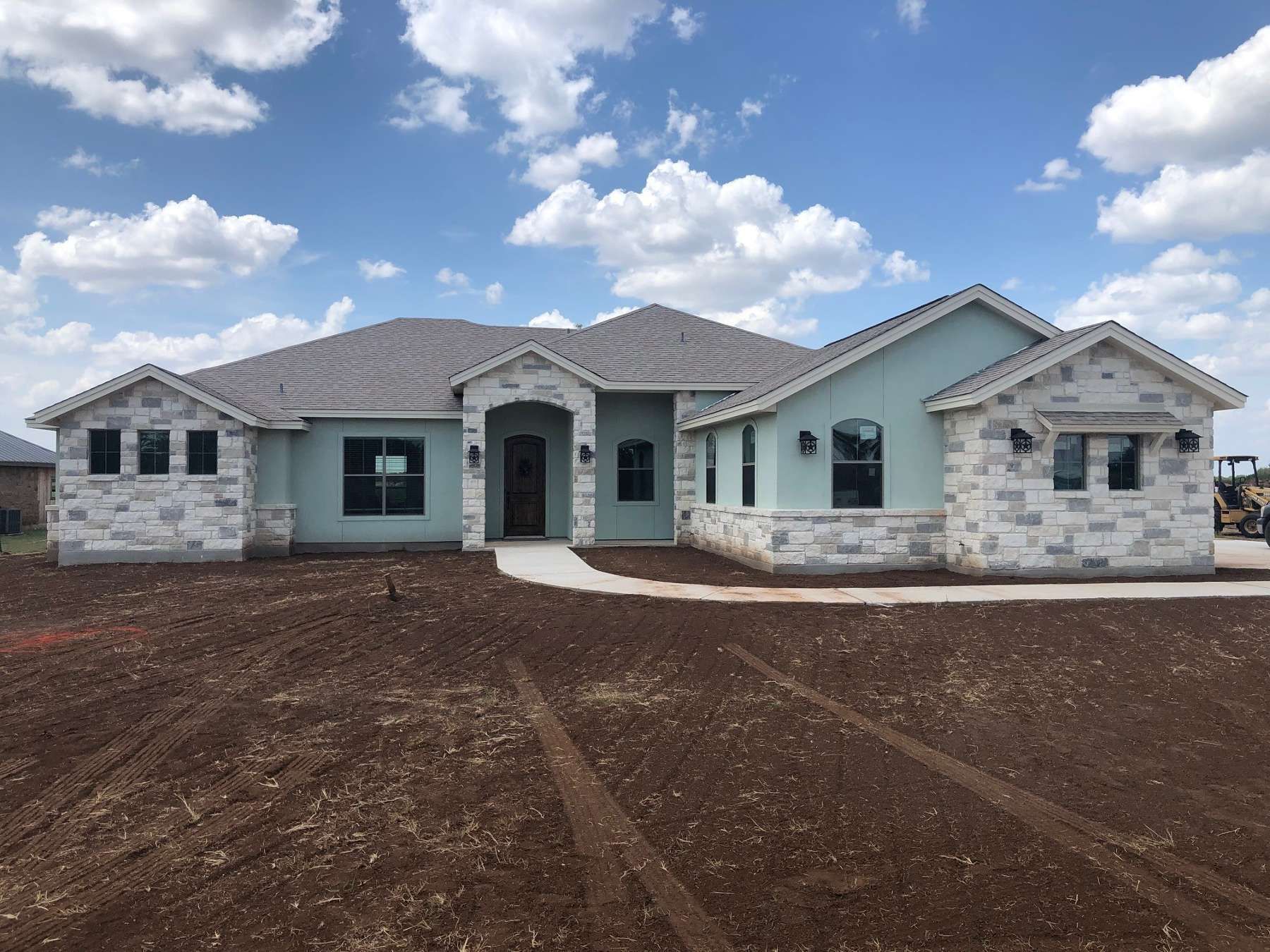A large house is sitting on top of a dirt field.