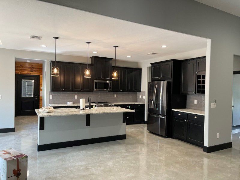 A kitchen in a house with black cabinets and stainless steel appliances.