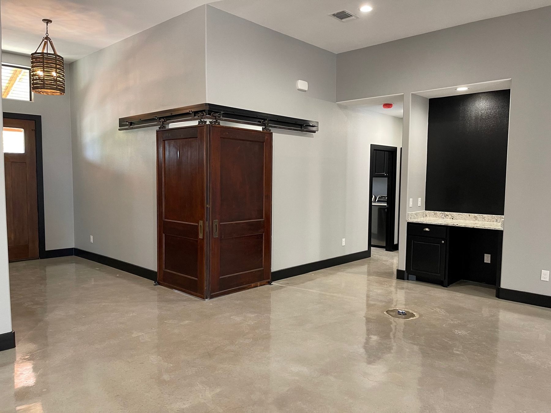 A large empty room with a sliding barn door in the corner.