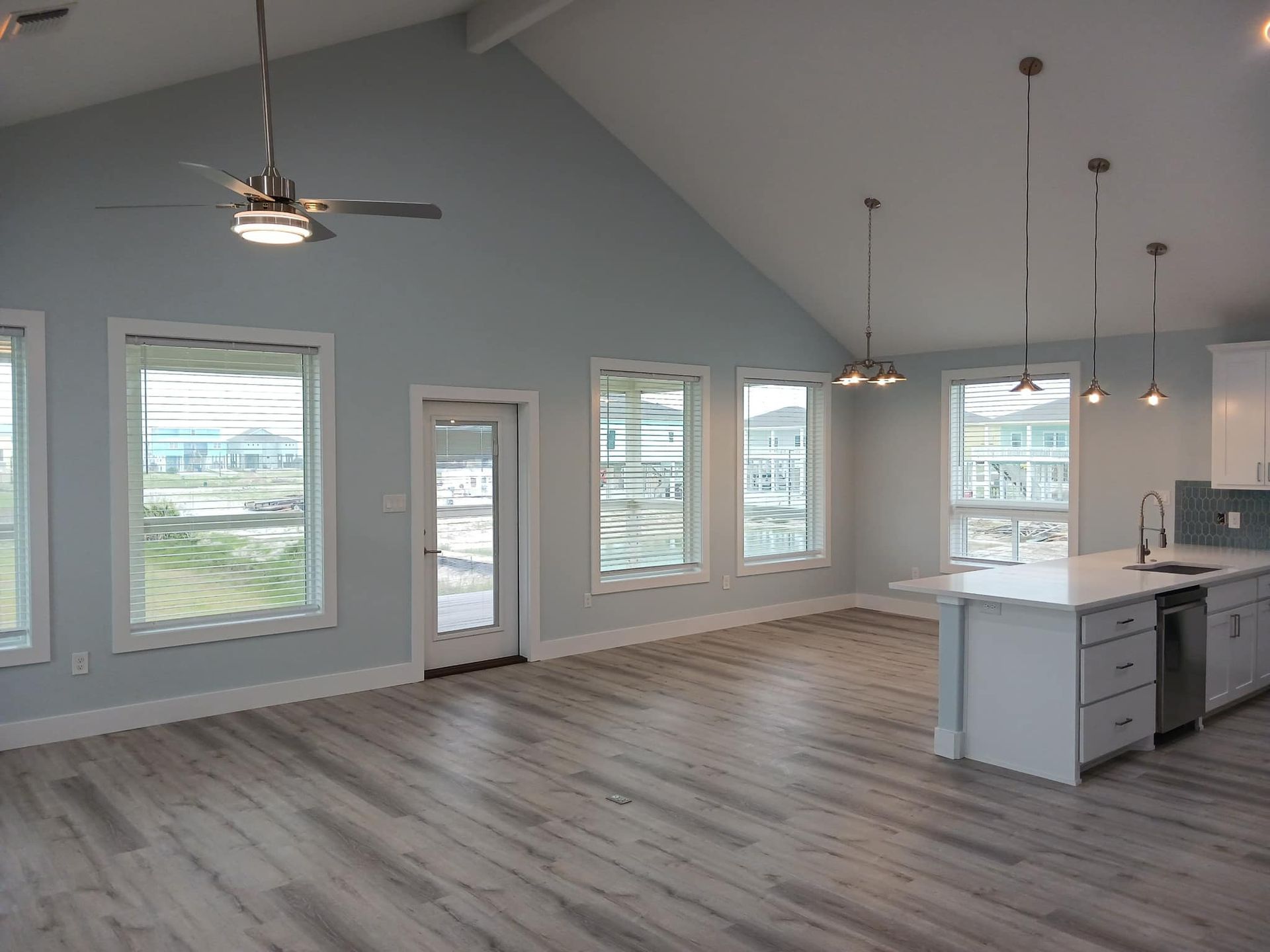 A large empty room with a lot of windows and a ceiling fan.