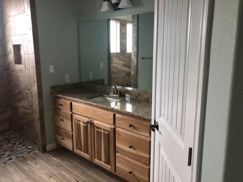A bathroom with two sinks , a mirror and a walk in shower.