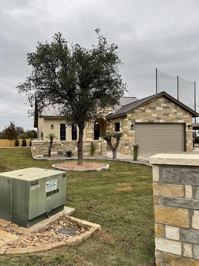 A house with a garage and a tree in front of it.