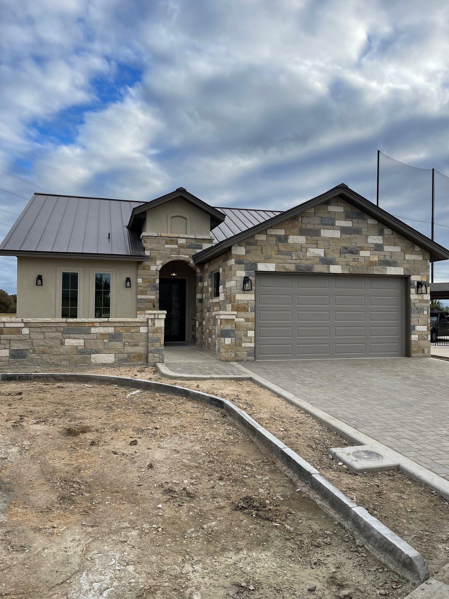 A house with a gray garage door is sitting on top of a dirt field.