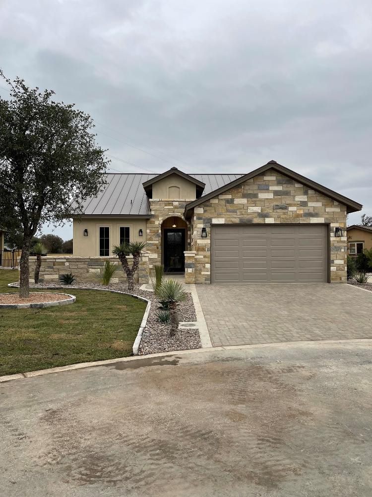 A large house with a garage and a tree in front of it.