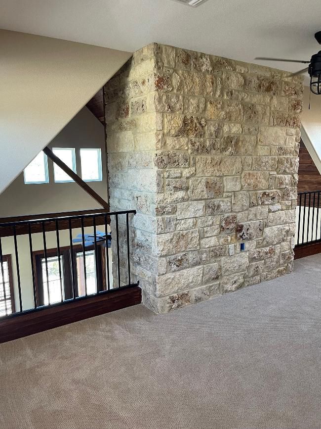 An empty room with a stone wall and a ceiling fan.