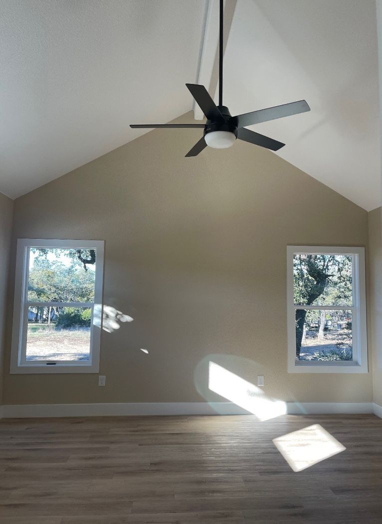 An empty room with a vaulted ceiling and a ceiling fan.