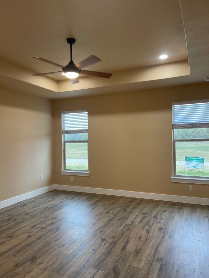 An empty living room with hardwood floors and a ceiling fan.